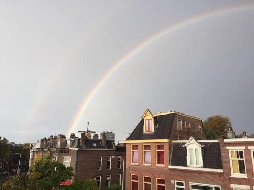 Ein Regenbogen am Himmel über einigen Gebäuden in der Unterkunft Tiny house for 2 with private garden in Utrecht