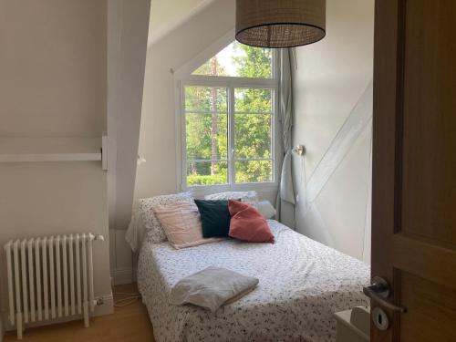 une chambre avec un lit avec des oreillers et une fenêtre dans l'établissement villa 7 chambres piscine 35 mn Paris, à Verneuil-sur-Seine