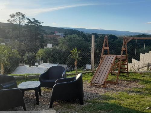 um parque infantil com cadeiras e um baloiço de madeira em ENCANTO SERRANO em Villa Carlos Paz