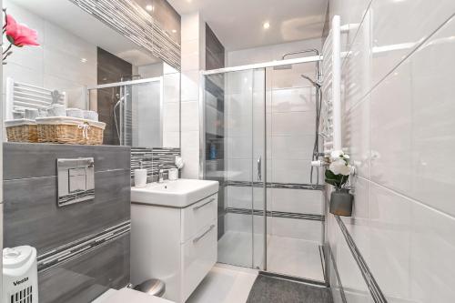 La salle de bains blanche est pourvue d'une douche et d'un lavabo. dans l'établissement Przestronne mieszkanie w centrum Gdańska, à Gdańsk