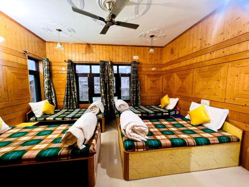 three beds in a room with wood paneling at Whostels Srinagar in Srinagar