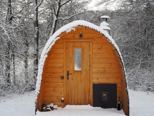 a wooden cabin with a door in the snow at Beniaskie! Lake Lodge in West Masuria in Miłakowo