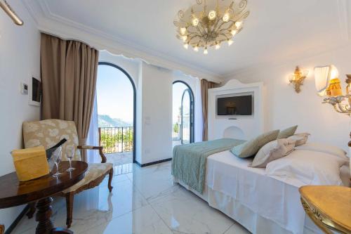 a bedroom with a bed and a table and a chandelier at Villa Amore Ravello in Ravello