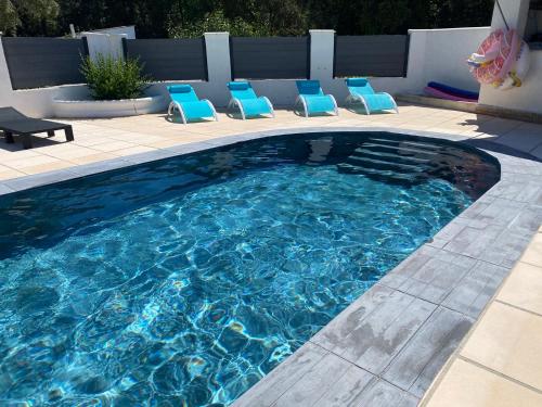 a swimming pool with blue lounge chairs in it at VILLA AVEC PISCINE in Néoules