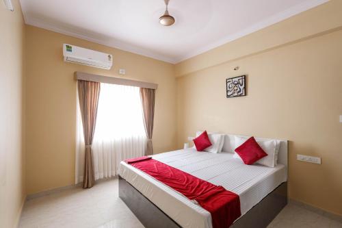 a bedroom with a bed with red pillows and a window at Classic Heights Serviced Apartments, near IIM Bangalore, in Bengaluru