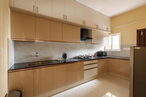 a kitchen with tan cabinets and black counter tops at Classic Heights Serviced Apartments, near IIM Bangalore, in Bengaluru