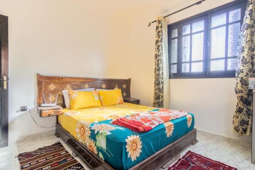 um quarto com uma cama com lençóis coloridos e uma janela em Appart Atlas em Marrakech