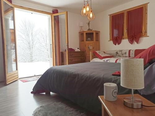 a bedroom with a large bed and a large window at Chambre d'hôte dans chalet près des pistes et aux départs de randonnées in Les Carroz d'Araches