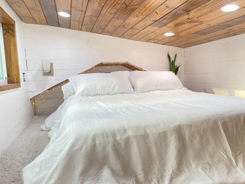 ein weißes Bett in einem Zimmer mit Holzdecke in der Unterkunft Bucks Pocket Little Secret 