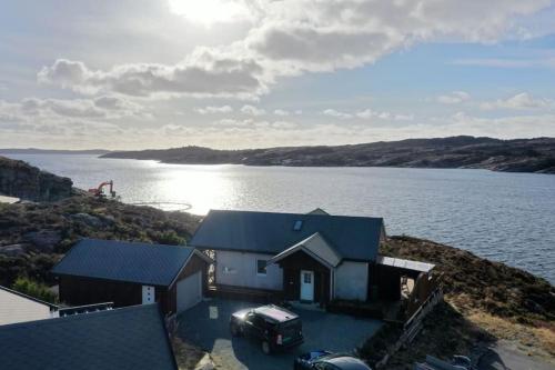 a house with a car parked next to a body of water at Fjordcabin Panoramic view Near Bergen 3 sleepingroom in Forland