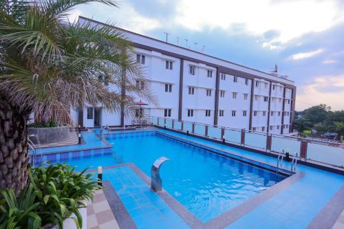 una piscina dell'hotel con un edificio sullo sfondo di Hotel PVK Grand Dindigul a Dindigul