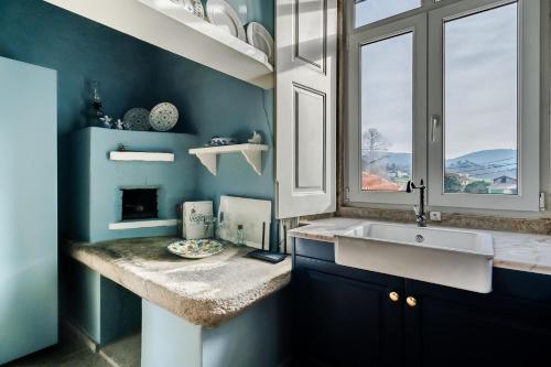 uma casa de banho azul com um lavatório e uma janela em Casa da Avó em Caminha
