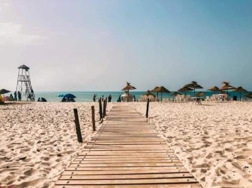 a wooden pathway on a beach with umbrellas at Villa archen in Soliman