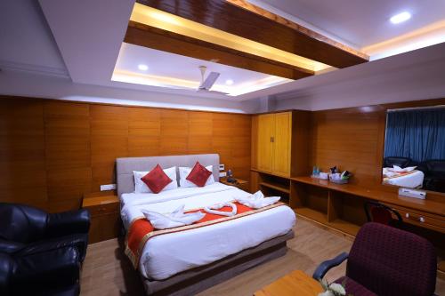 a hotel room with a bed and a desk and chair at Hotel PVK Grand Dindigul in Dindigul