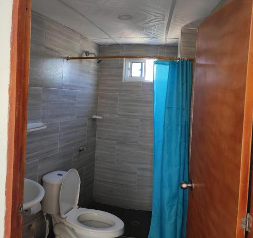 a bathroom with a toilet and a blue shower curtain at Emvacamo' in Taganga