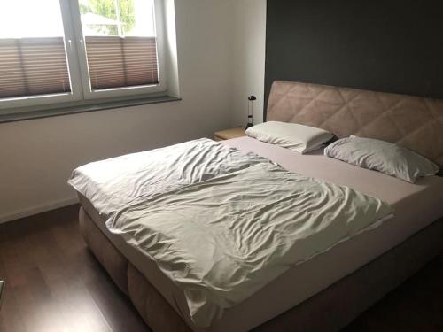 Una cama con sábanas blancas y almohadas en un dormitorio en Stilvolles Apartment - mit E-Auto Lademöglichkeit en Attendorn