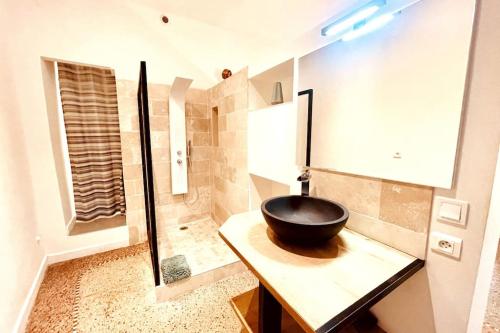 La salle de bains est pourvue d'un lavabo noir sur un comptoir. dans l'établissement Cachet Cosy, à Nîmes