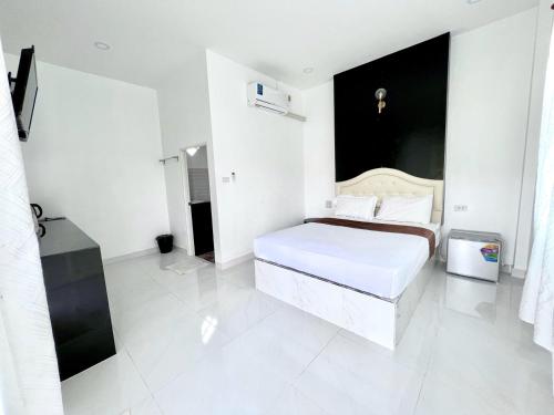 a white bedroom with a bed and a black wall at Rim Suan Resort in Satun