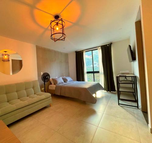 a bedroom with a bed and a couch and a chandelier at Trip Monkey del Río in San Gil