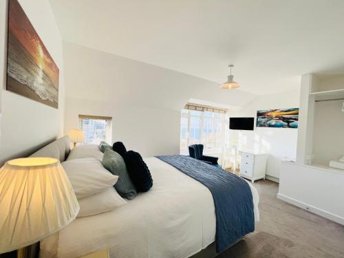 a bedroom with a large white bed and a lamp at Lundy SeaView Great Sea-views in Westward Ho