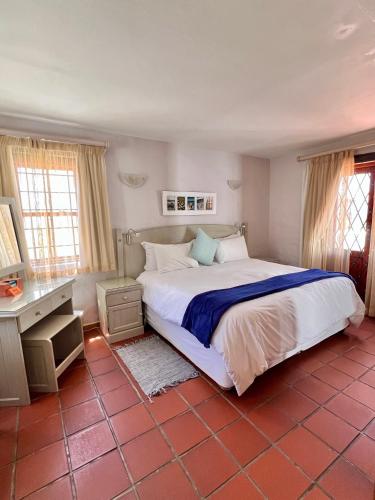 a bedroom with a large bed and a desk at Baywatch Paternoster -The Villa in Paternoster