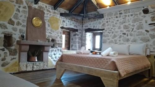 ein Schlafzimmer mit einem Bett in einem Zimmer mit Steinwänden in der Unterkunft Neromilos Monastiraki Vonitsas in Monastirákion