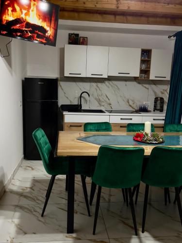a kitchen with a wooden table and green chairs at Cabana Lavinia Daniel in Statiunea Borsa