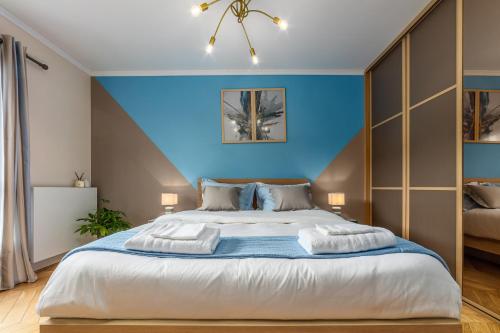 a bedroom with a large bed with a blue wall at SUITE ET CHAMBRES COSY CHEZ A&M -ELEGANT HOME, CALME, CAMPAGNE, PARKING gratuit in Épône