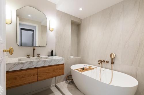 une salle de bain avec une baignoire, un lavabo et un miroir dans l'établissement Elegant apartment - Paris 6th - 4p, à Paris