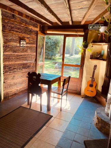 a table and chairs in a room with a guitar at El Hobbit in Villa General Belgrano