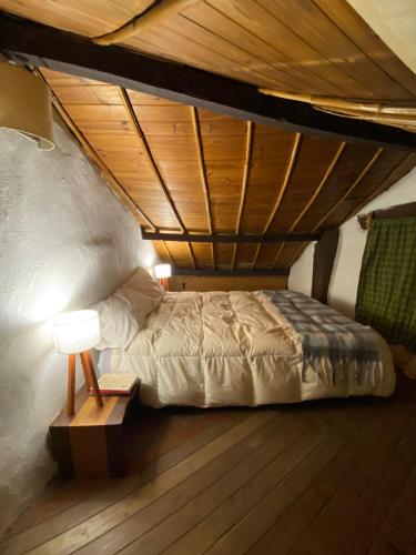 a bed in a room with a wooden ceiling at El Hobbit in Villa General Belgrano