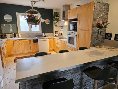 une cuisine avec des armoires en bois et un comptoir dans l'établissement Villa Spacieuse - Vue Montagne et Château, à Lavelanet