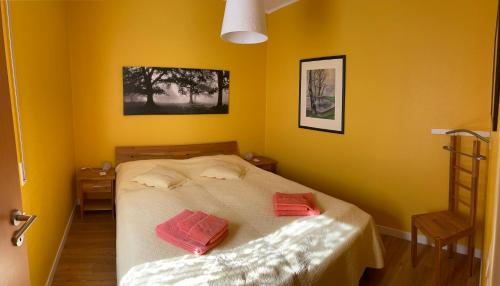 ein gelbes Schlafzimmer mit einem Bett mit zwei Handtüchern darauf in der Unterkunft Traumhaus am Maar 1 in Schalkenmehren