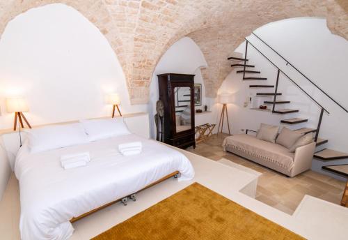 a bedroom with a white bed and a staircase at Dimora del Vico - Exclusive Terrace with View in Cisternino