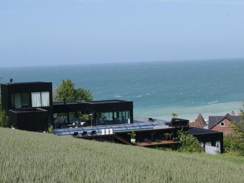 une maison sur une colline avec l'océan en arrière-plan dans l'établissement La résidence de la Villa Quartz, à Varengeville-sur-Mer