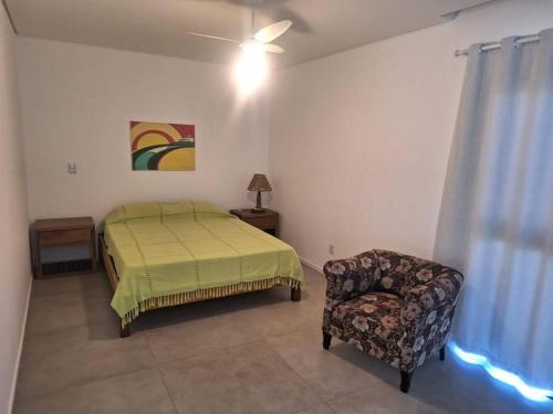 1 dormitorio con 1 cama y 1 silla en Casa familiar em Garopaba, en Garopaba