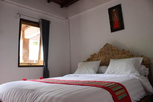 a bedroom with a large bed with white sheets and a window at Private Villa Kayu Padangbai in Padangbai