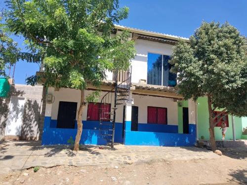 a house with blue and white walls and trees at Emvacamo' in Taganga