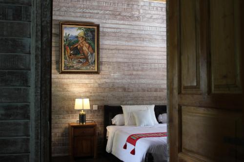 a bedroom with a bed and a painting on the wall at Private Villa Kayu Padangbai in Padangbai