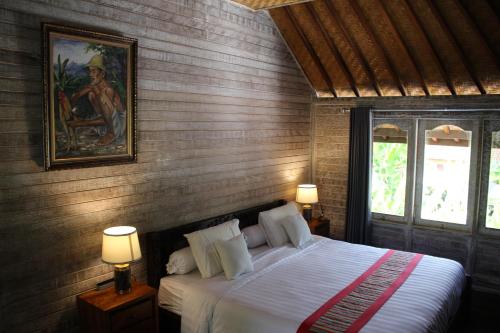 a bedroom with a bed with a painting on the wall at Villa Kayu Padangbai in Padangbai