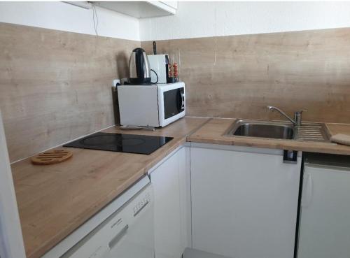 une petite cuisine avec un micro-ondes et un évier dans l'établissement Le Triplex de la gare - centre ville - wifi, à Bordeaux