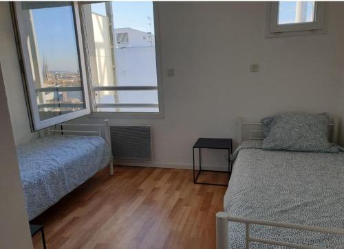 une chambre avec deux lits et deux fenêtres dans l'établissement Le Triplex de la gare - centre ville - wifi, à Bordeaux