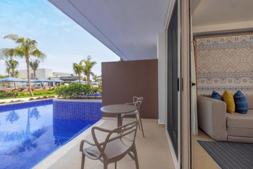 a balcony with a table and chairs next to a swimming pool at Royalton Splash Riviera Cancun, An Autograph Collection All-Inclusive Resort in Cancún