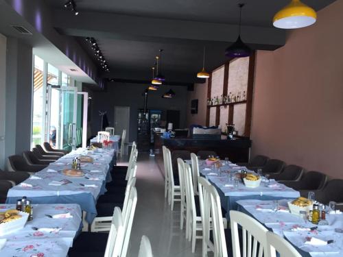 uma sala de jantar com mesas longas e cadeiras brancas em Hotel Zogu em Bulqizë
