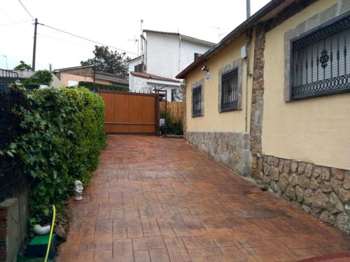 a brick walkway next to a house with a fence at Casa rural Higueras in Santa María de la Alameda
