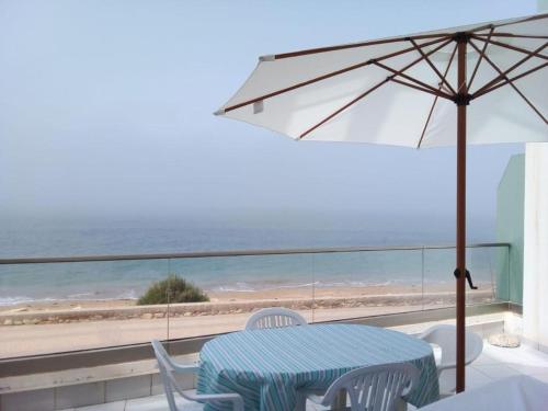 a table and chairs with an umbrella and the beach at Holikeys - Agadir - 2 Ch - Aourir 005 in Agadir