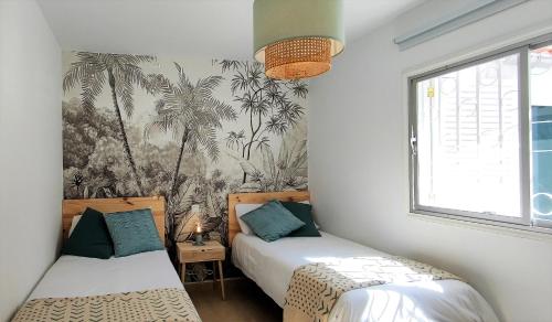 a bedroom with two beds and a palm tree wallpaper at Bungalow Céntrico & Tranquilo in San Bartolomé de Tirajana