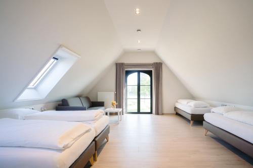 a attic room with several beds and a window at Vakantiewoning Amico in Gistel