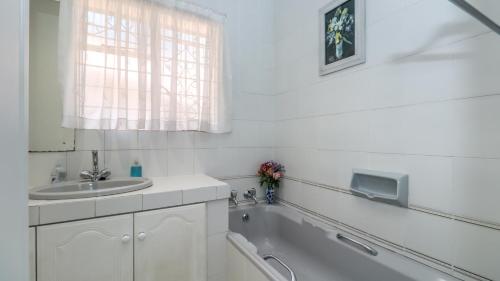 a white bathroom with a sink and a bath tub at BEDFORDVIEW BandB in Bedfordview