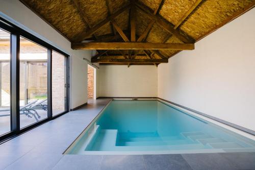 an empty swimming pool in a room with windows at Vakantiewoning Amico in Gistel